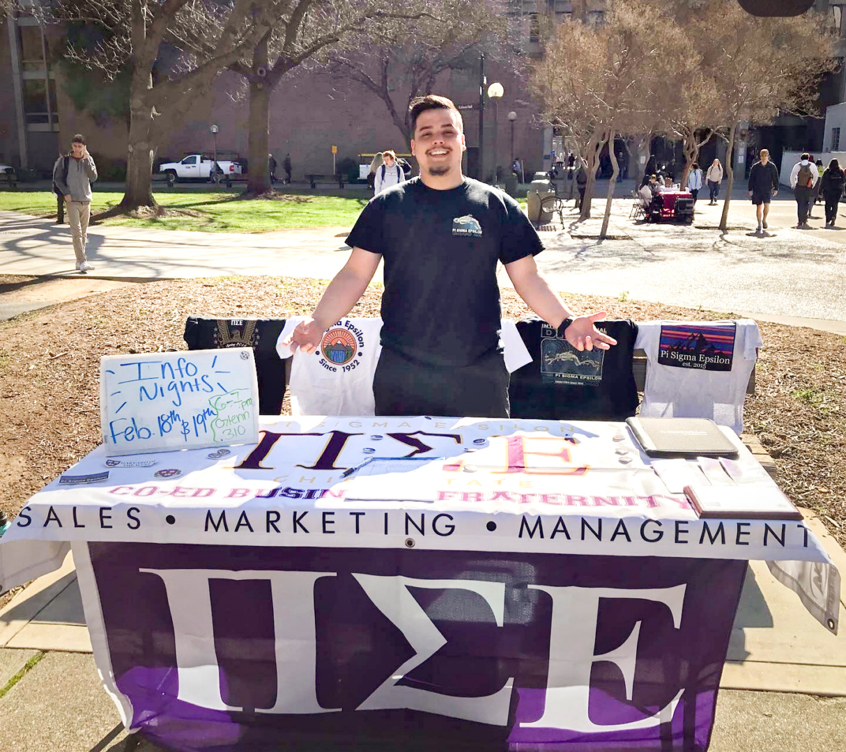Ryan Lobsien stands in front of a table for Pi Sigma Epsilon.