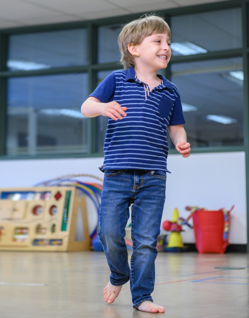 Grayson Pickering smiles as he runs barefoot in the autism clinic.