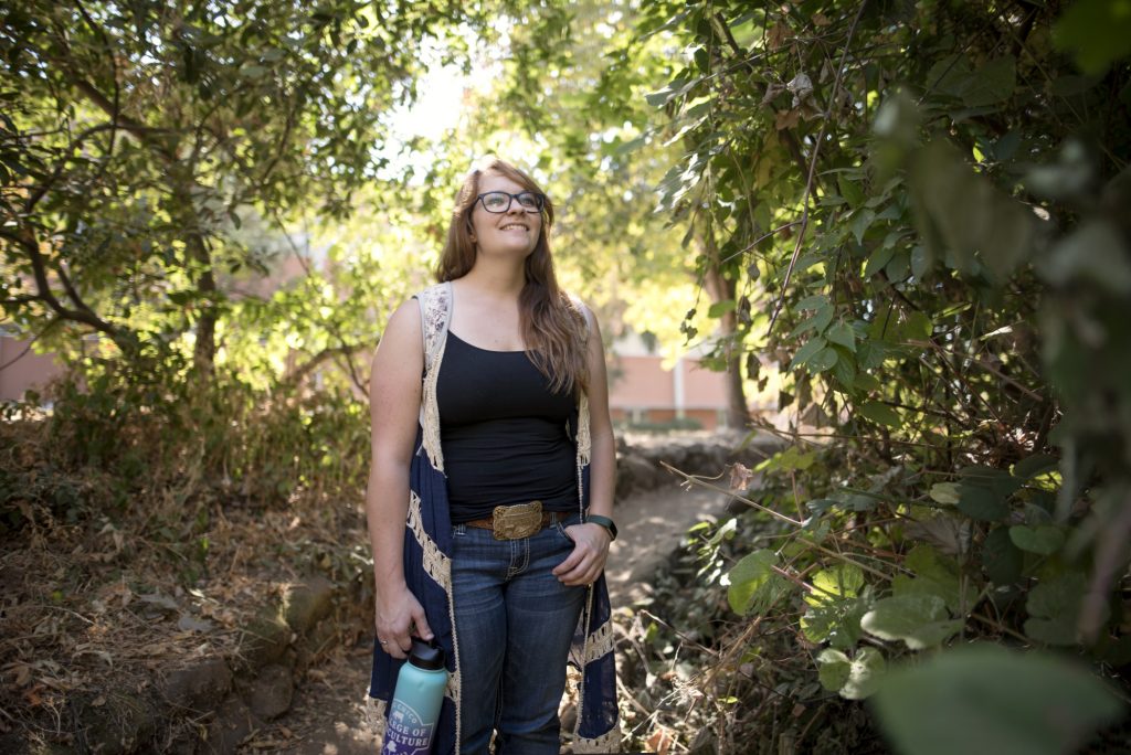Kiena Sanders poses for a photo along the wooded walking path near the creek on campus.