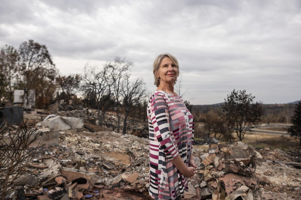 Shannon Phillip stands in the ruins of a home that was burnt to the ground by the Carr Fire.