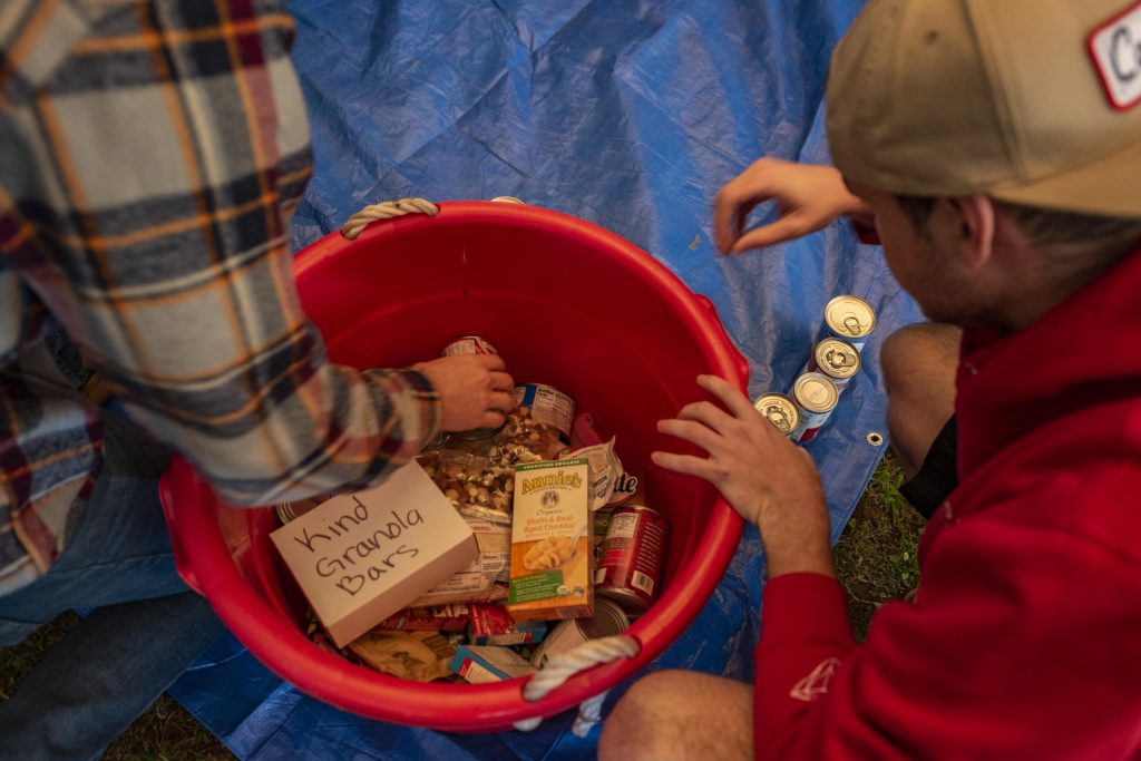 Students fill a large bucket full of canned and boxed foods.