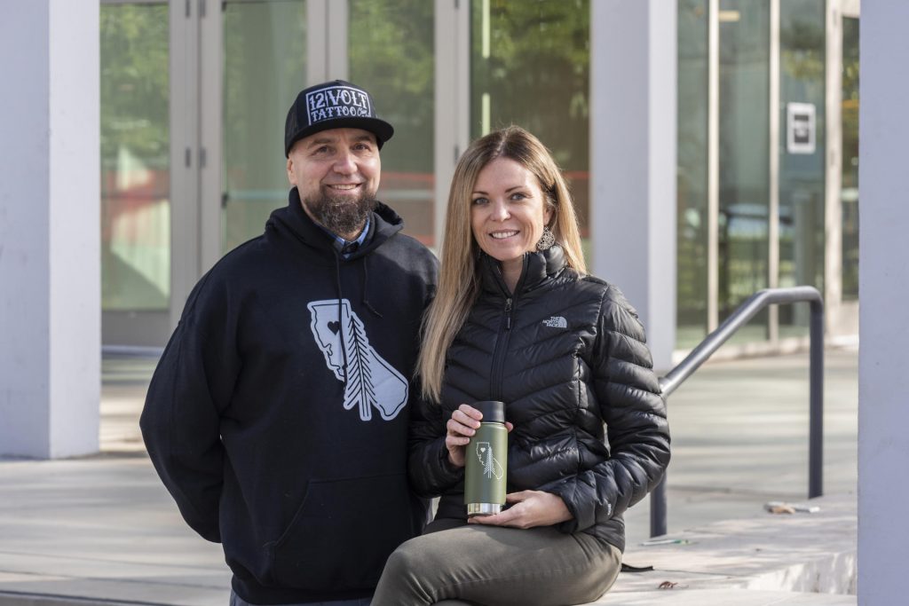 Karen and Zac Acker sit on the Chico State campus holding one of the Klean Kanteen insulated bottles with the Butte Strong design
