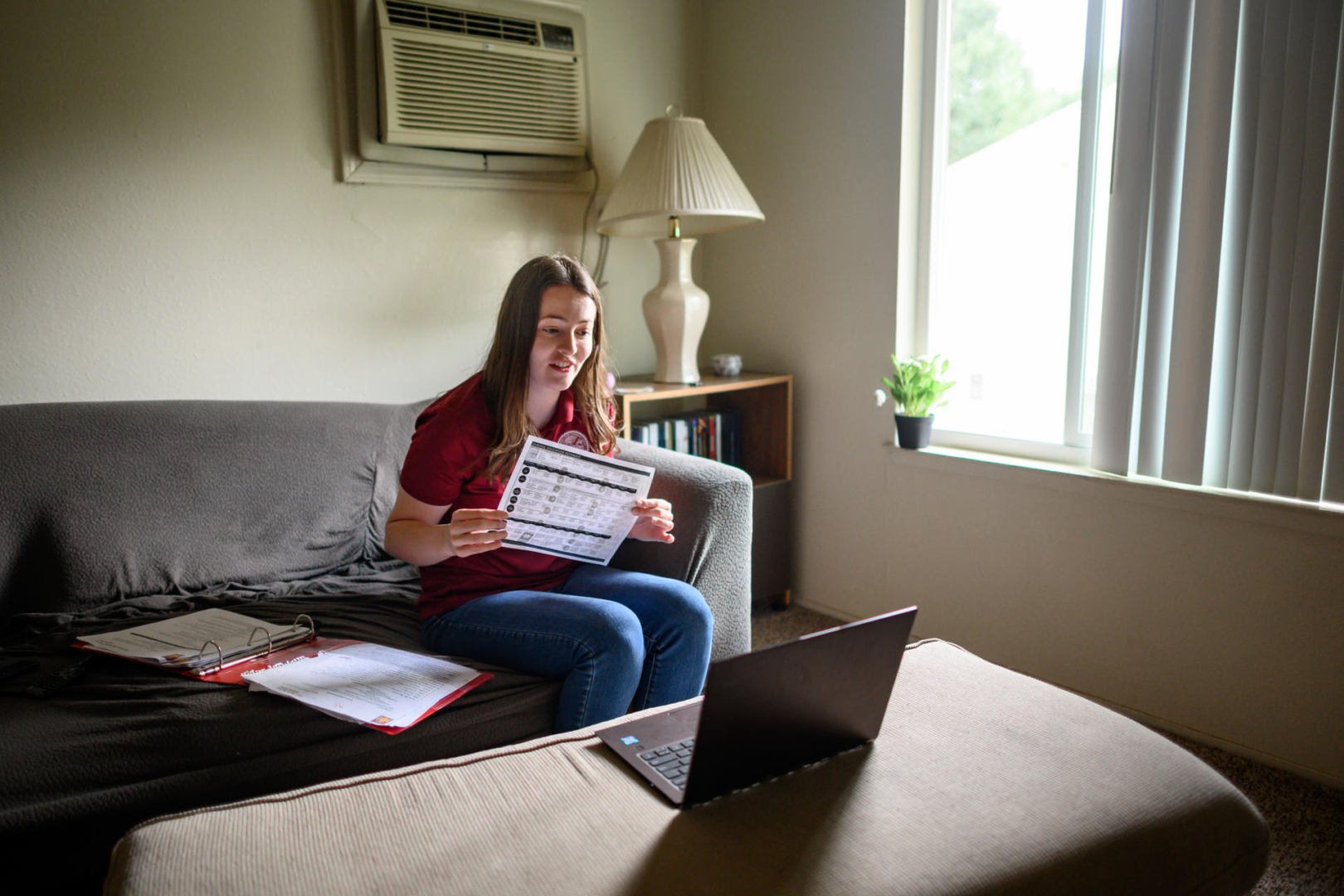 A student sits on her couch at home while she talks with others on a Zoom call