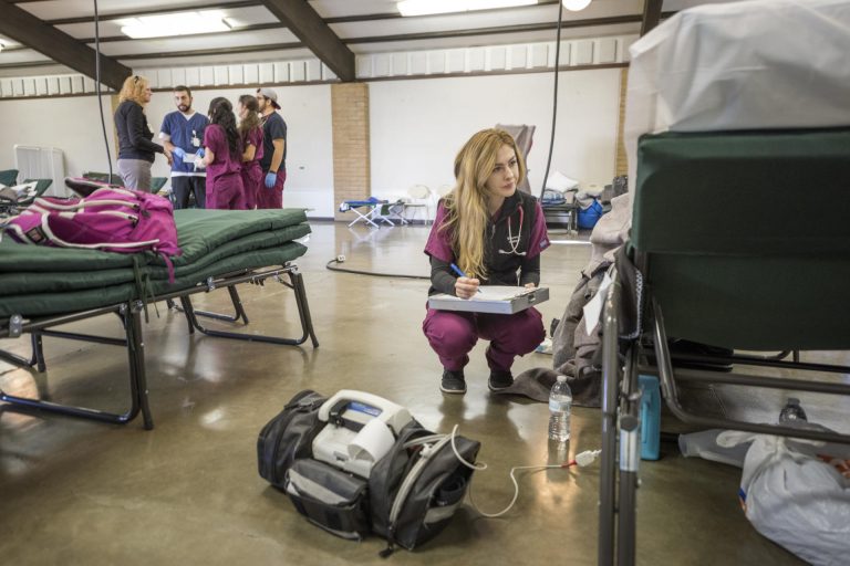 A nursing student crouches down to help a patient at an evacuation center during the Oroville Dam crisis in February 2017.