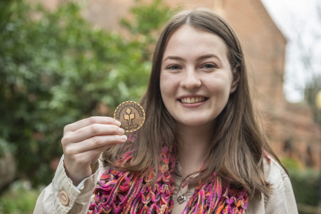 Emily Zarback holds the Presidential Medallion she received from Chico State President Gayle Hutchinson.