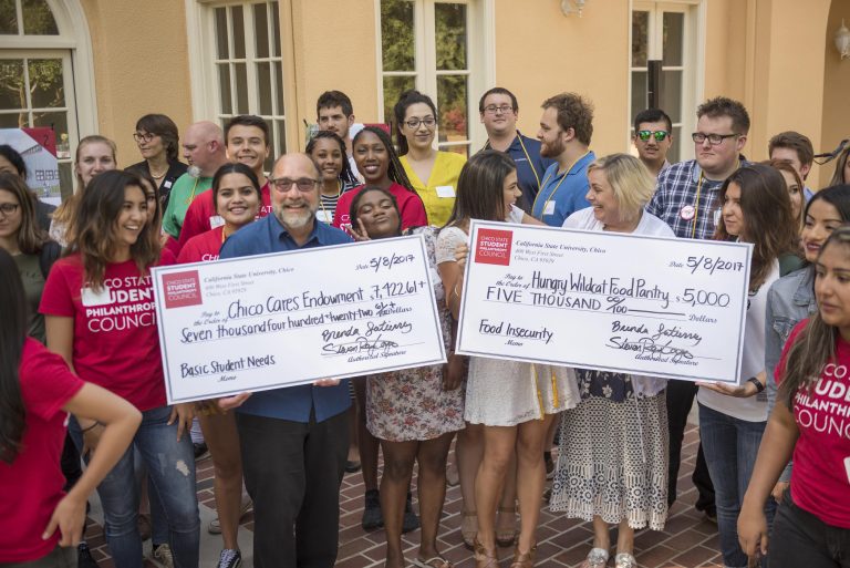Students from the Student Philanthropy Council crowd behind Joe Picard and Kathleen Moroney as they both hold over-sized checks.