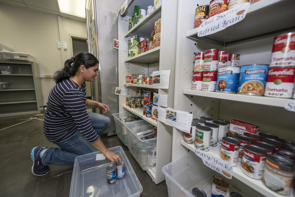 Inderpal Bajwa stocks the shelves of the Hungry Wildcat Food Pantry full with donations.