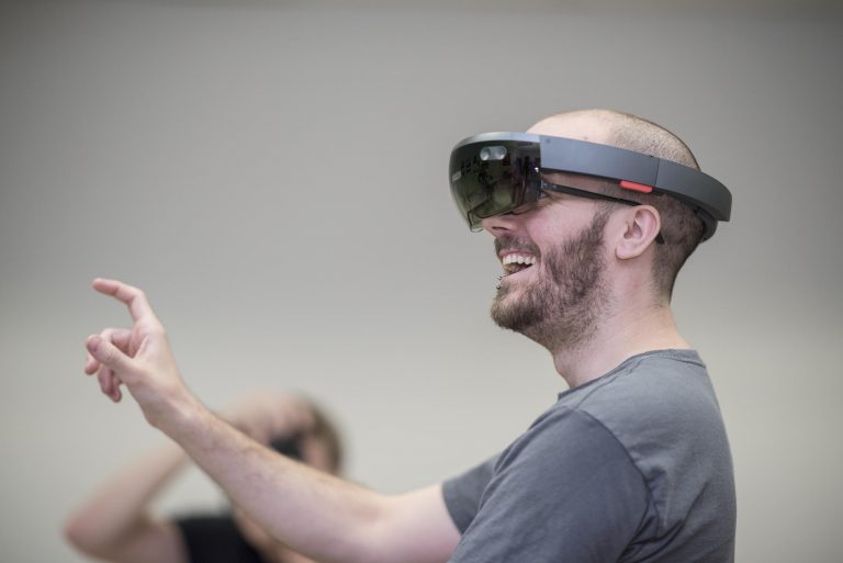 Lance Mitchell extends his hand to touch his virtual surroundings while wearing the Microsoft HoloLens.