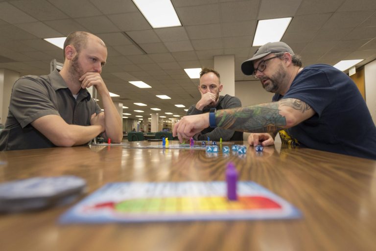 Three campus faculty and students playing the game Dicey Peaks.