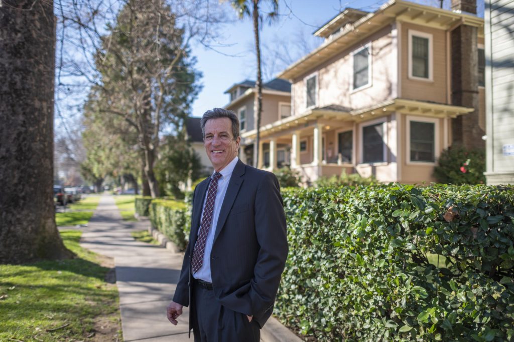 Dan Herbert smiles while standing in a neighborhood of student housing.