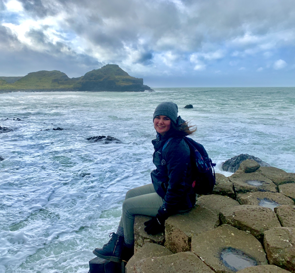 Jenessa Ramirez sits on the edge of the ocean in Ireland.