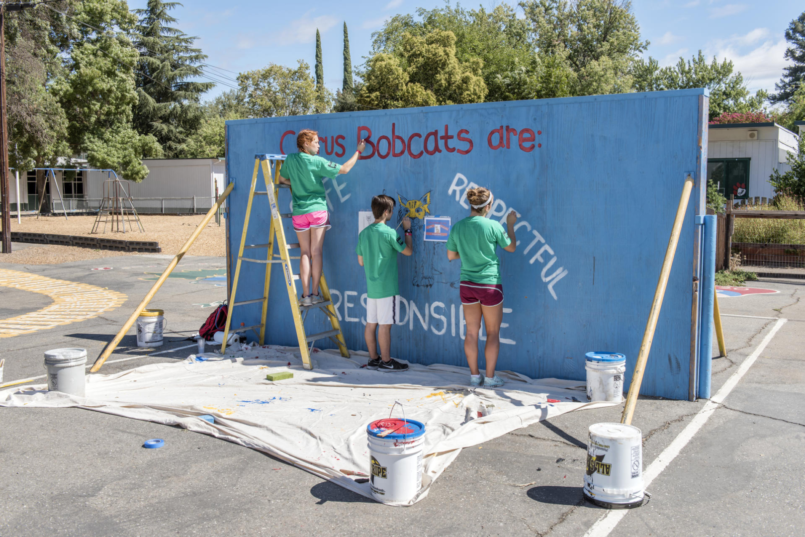 Students paint a mural on a backboard for playing ball at Citrus Elementary.