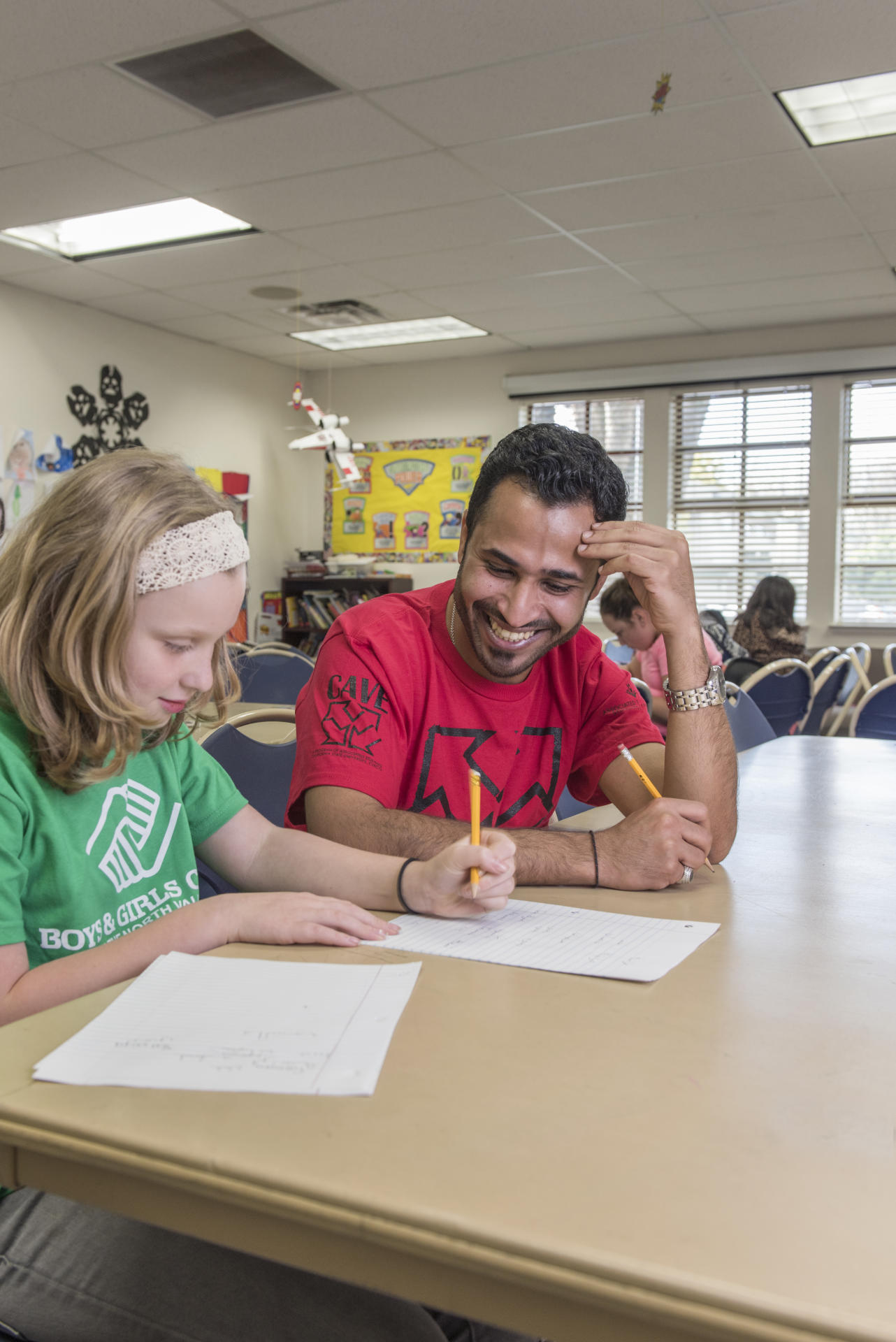 A student works teaches a girl at the Boys and Girls Club how to write in Arabic as part of a volunteer program.