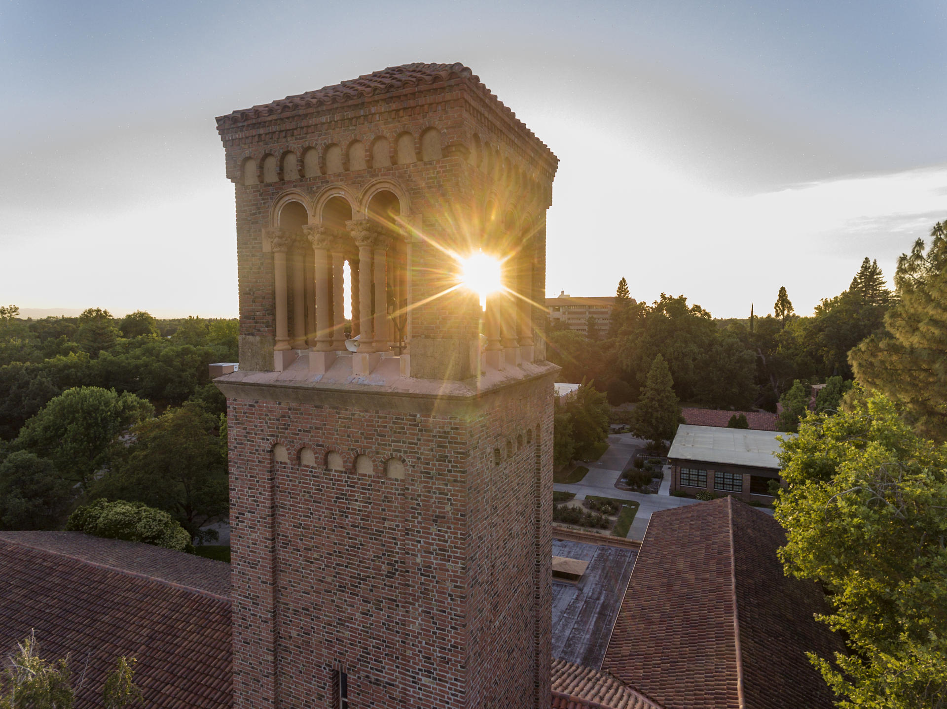 A drone photograph shows a late-spring sunset shining through Trinity Hall.