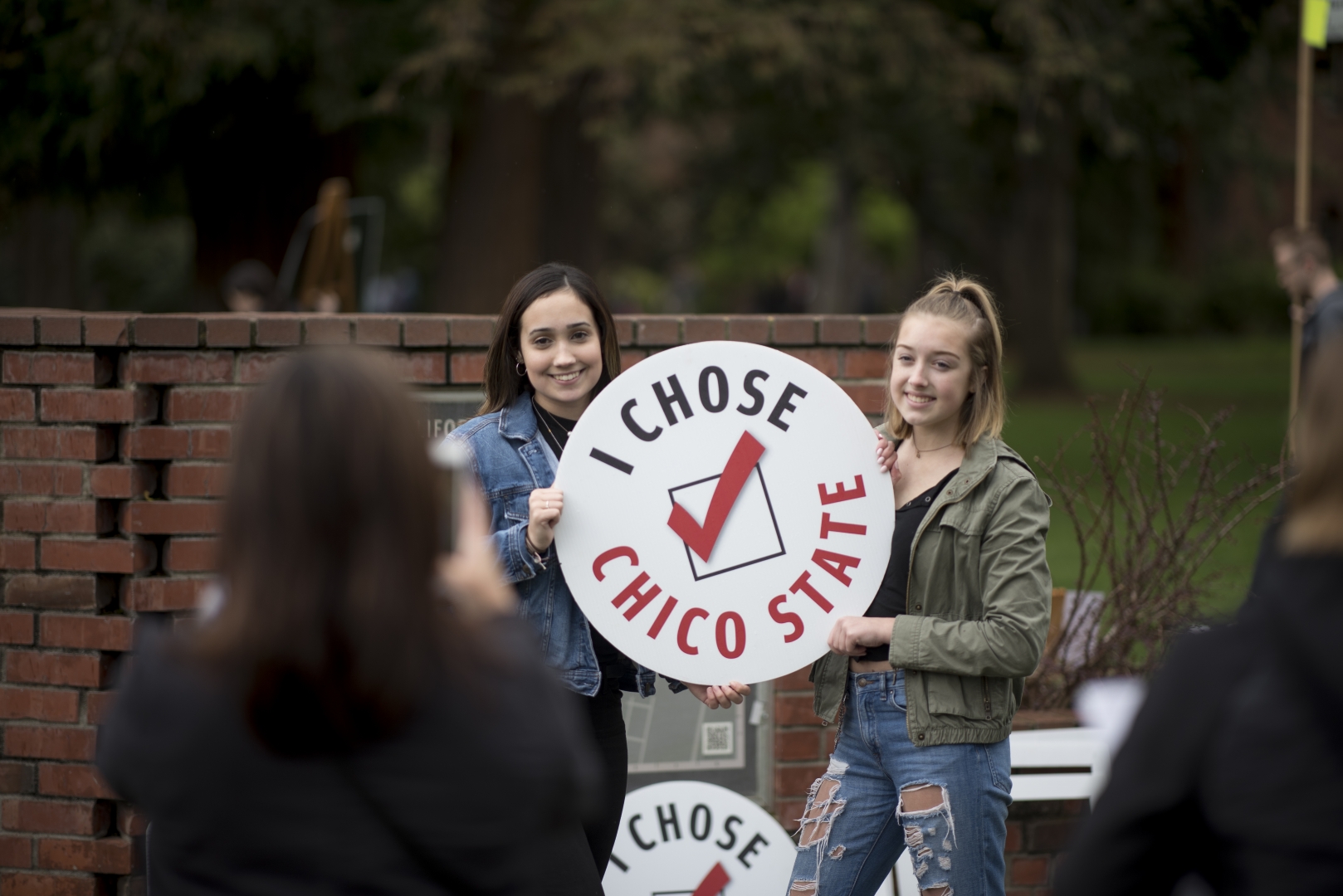 Two students smile and hold a round sign that reads "I chose Chico State" during Choose Chico.