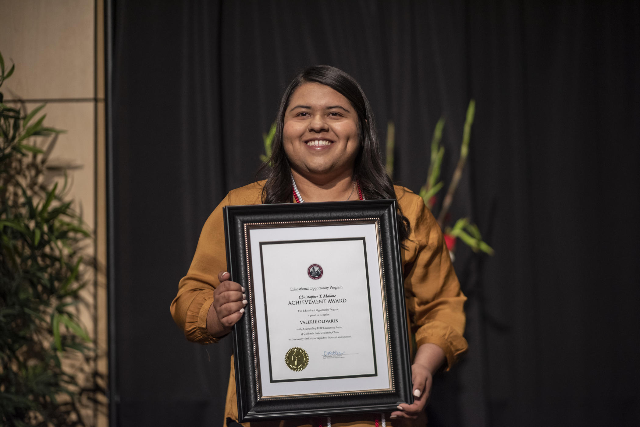Valerie Olivares holds a framed award.