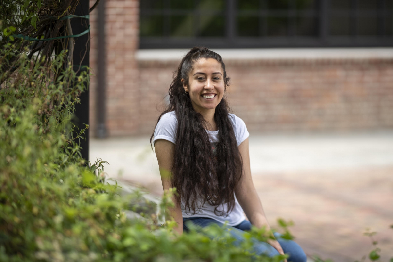 Chico State student Angela Serrano sits on a bench outside brick-lined Colusa Hall.
