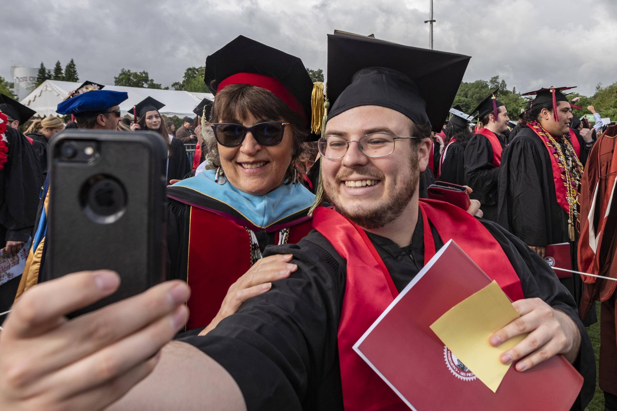 President Hutchinson and Joseph Arballo pose for a selfie at graduation, both in their regalia.