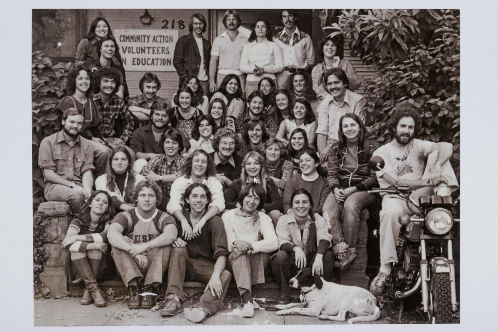 A historic photo of CAVE shows its staff sitting on the building stairs in the early 1970s.
