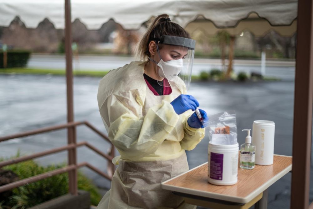 A nursing student wearing personal protective equipment finishes administering a COVID-19 test.