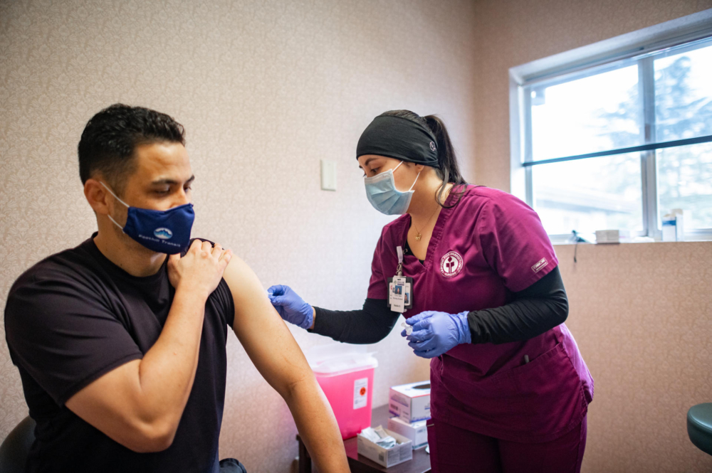 A nursing student prepares the arm of a recipient of a vaccination.