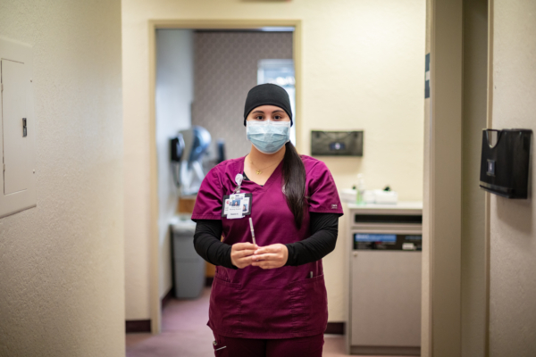A nursing student wearing protective gear holds a syringe that contains the vaccine against the coronavirus.