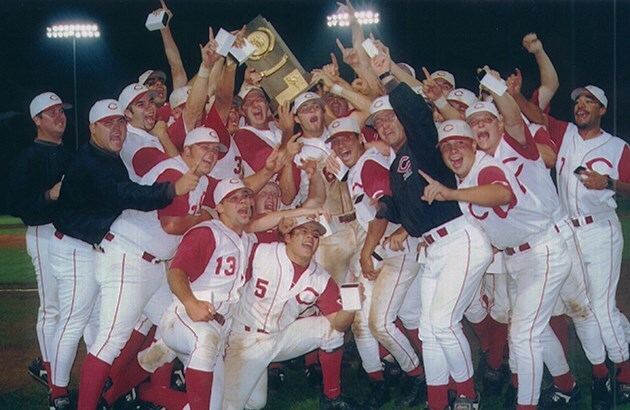 The 1999 baseball team holds up the national trophy and cheers after winning.