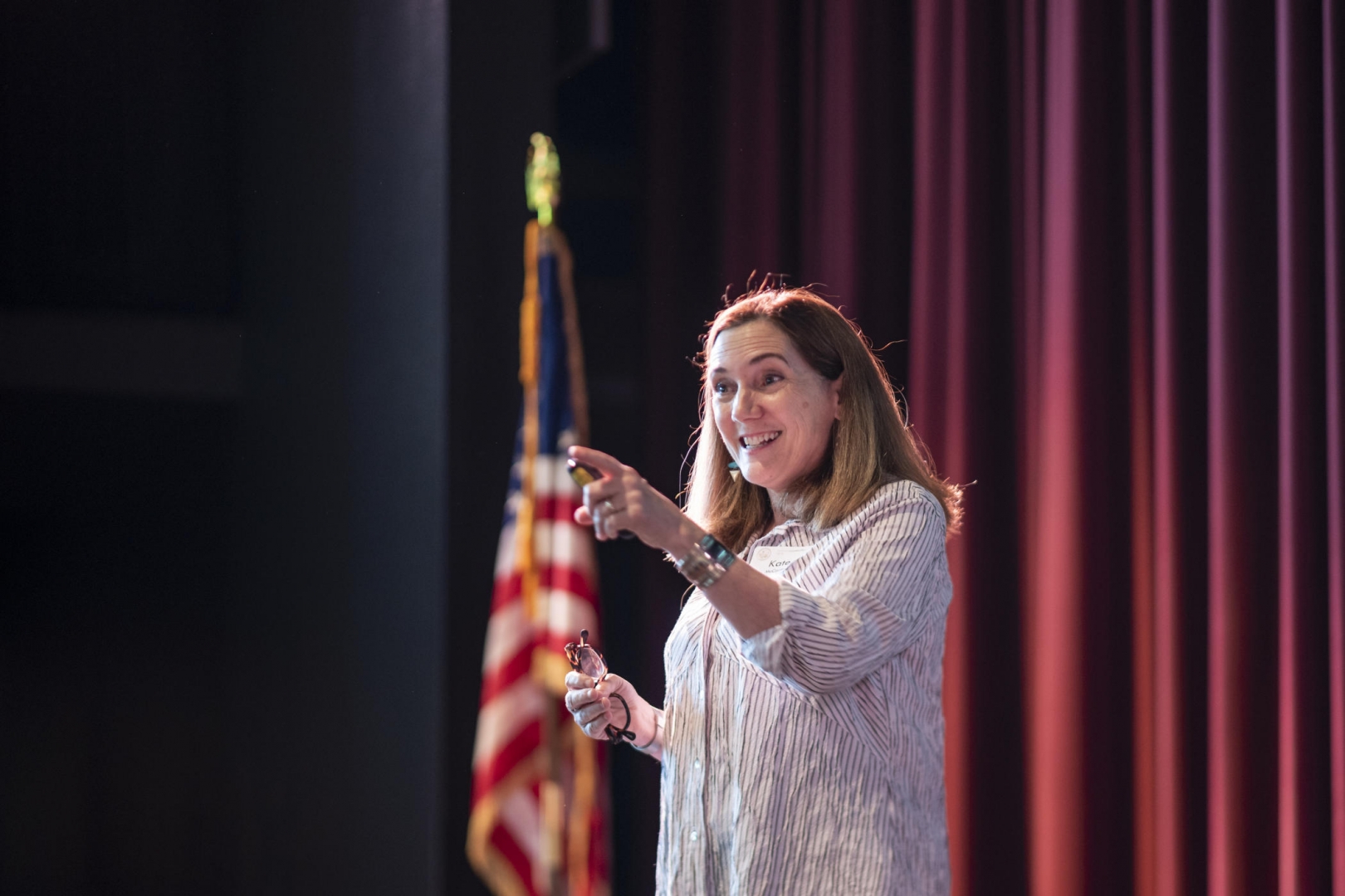 Kate McCarthy smiles and gestures to an audience member as she speaks on stage.