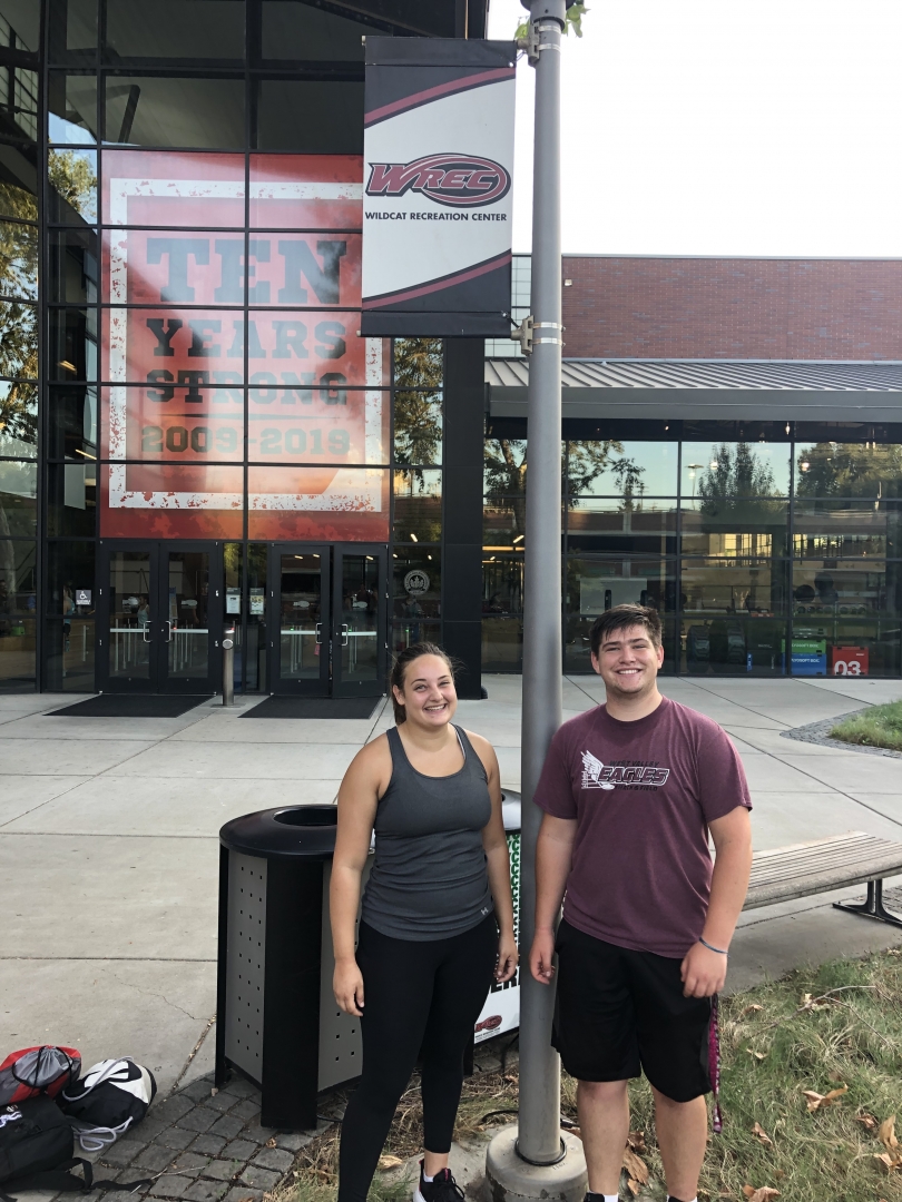 Payton and a female athlete pose in front of the WREC.
