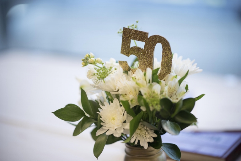 A flower arrangement with the number 50 sits on a table.