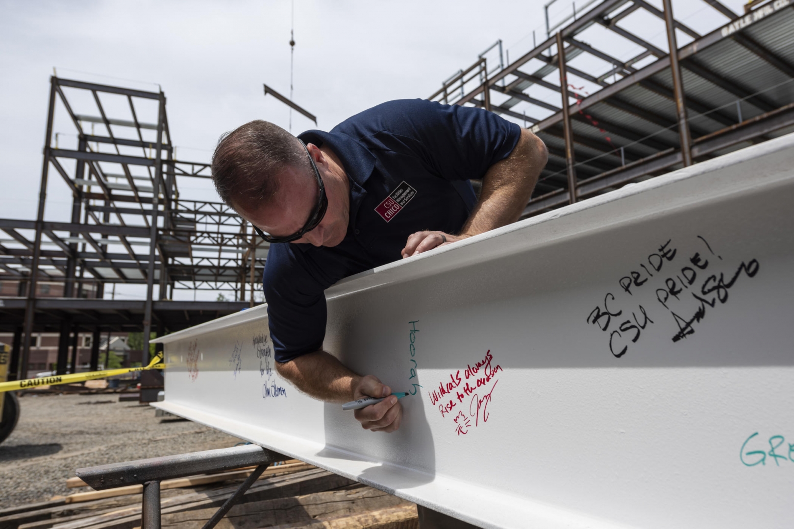 Mike Guzzi signs "Hoorah" on a steel beam in the new physical sciences building.