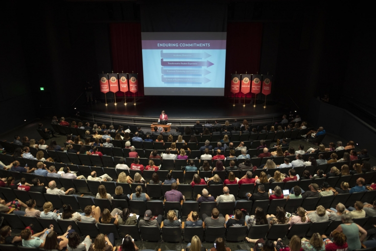 A matrix of the Strategic Plan lights up on a screen on the Harlen Adams Theatre stage to a crowd of hundreds in the audience.