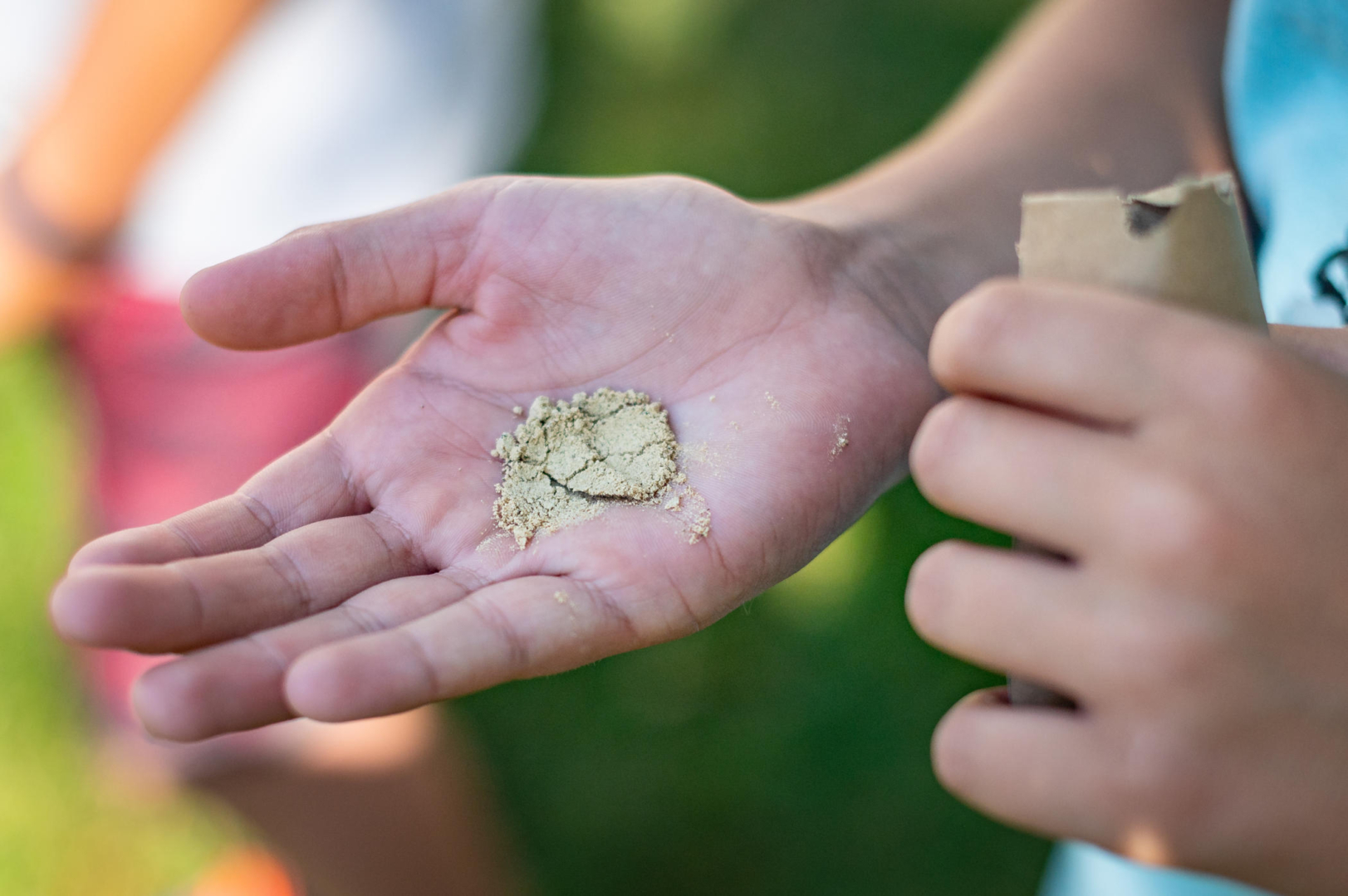 A child holds almond flour in the palm of their hand.