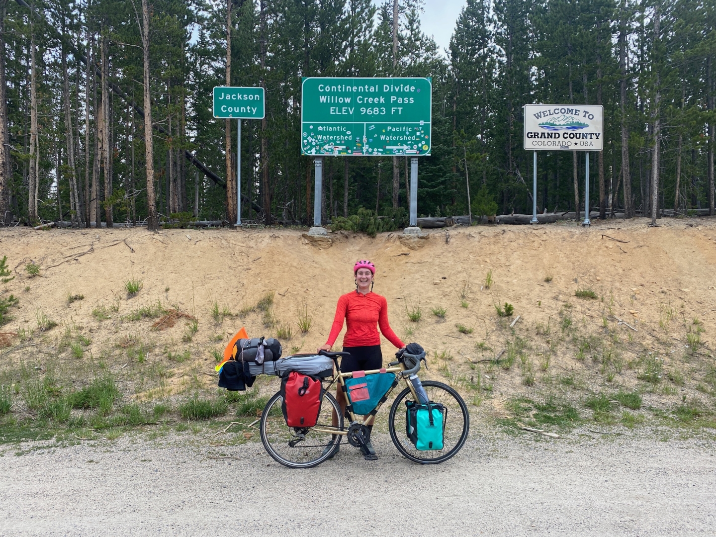 Christine Wilhoyt poses with her bike next to a sign marking the Continental Divide.