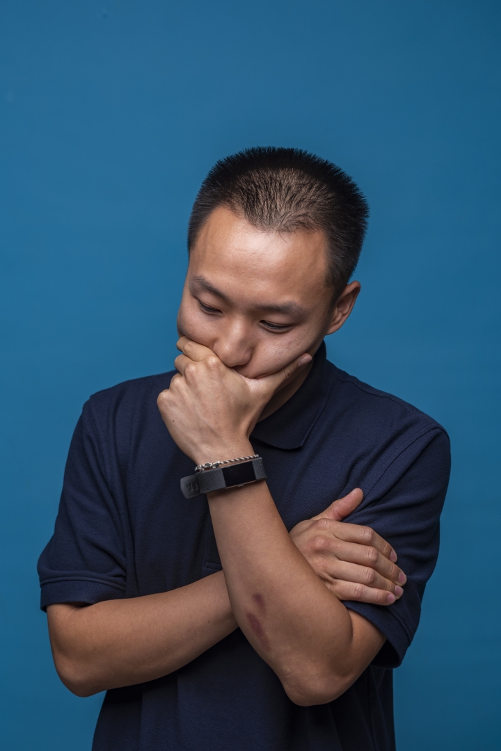 Kosue Yang folds his arm and holds his face in one hand, contemplative