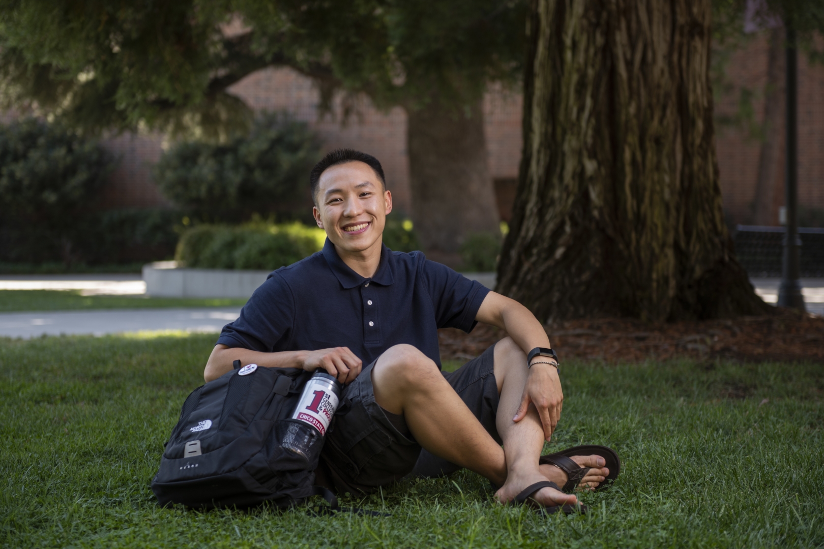 Kosue Yang sits cross-legged on Kendall Lawn, smiling