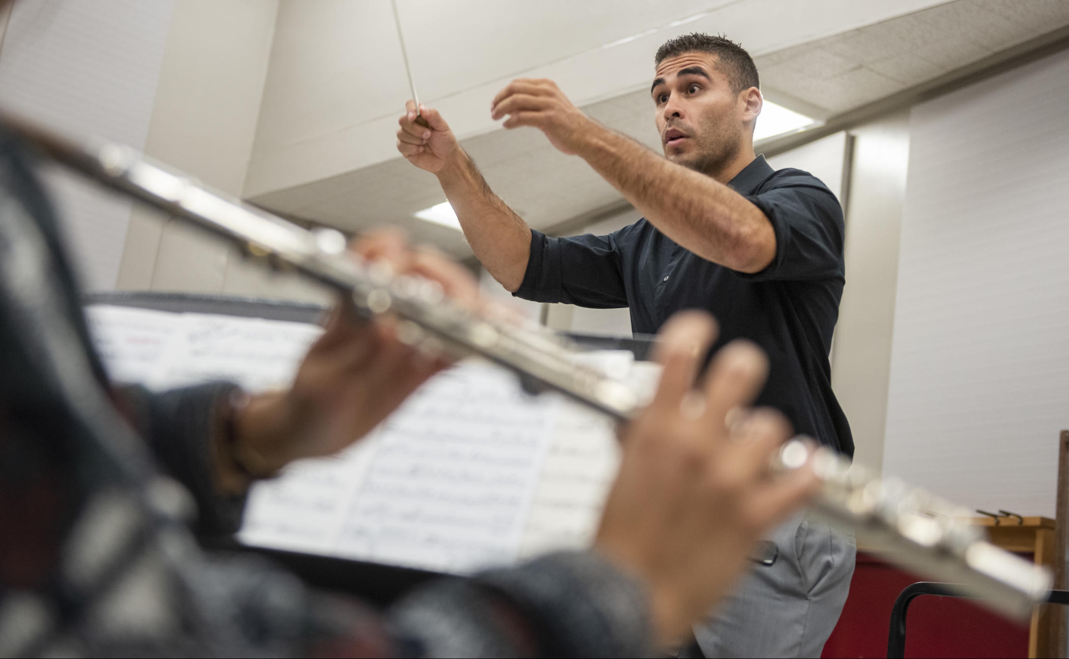 Chris Navarrete conducts a music rehearsal with a clarinet player playing in the foreground