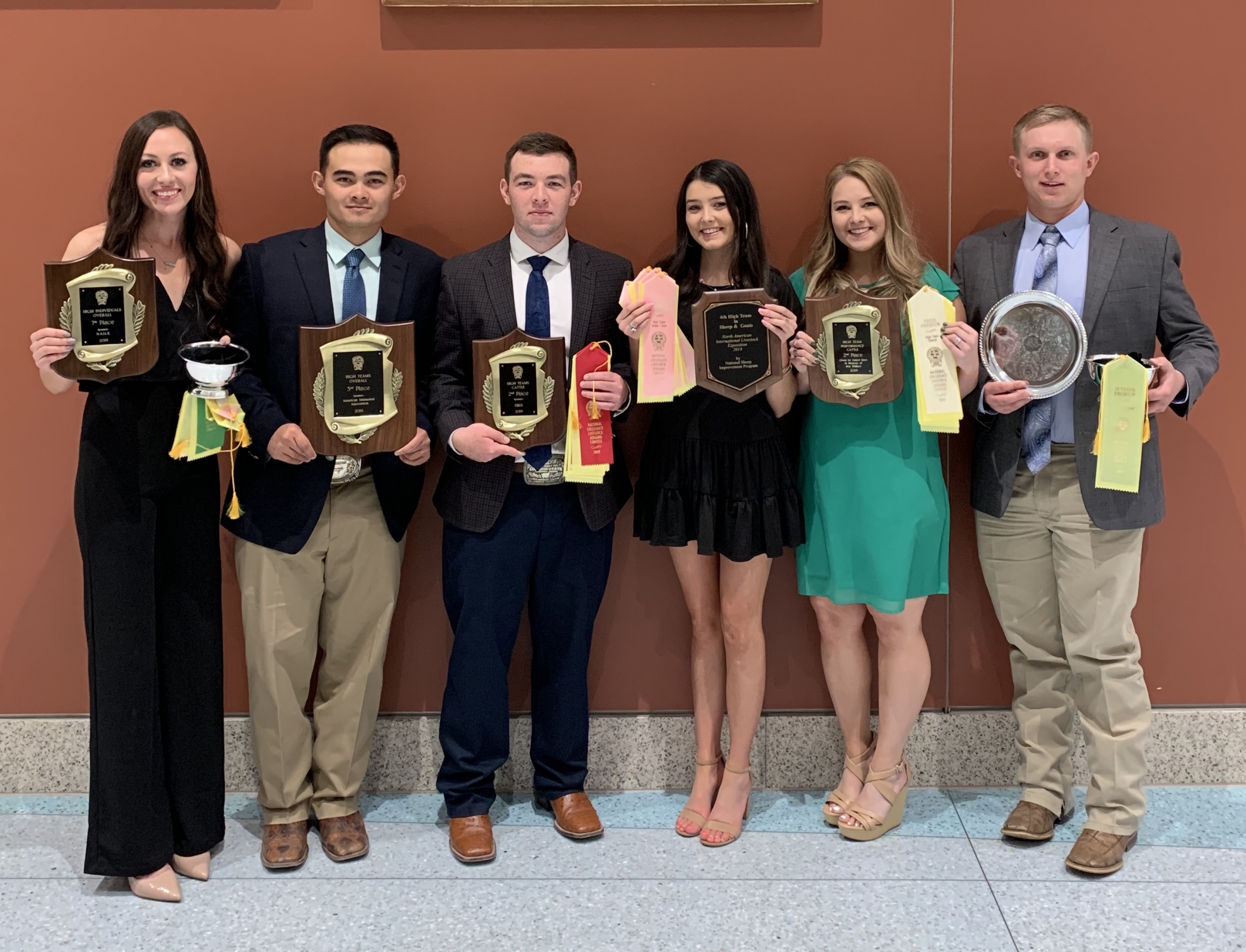 Six college students smile and hold awards.