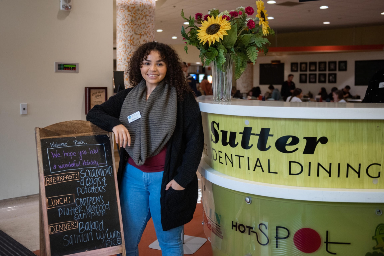 Jessica is standing in Sutter Dining, leaning against a sign.