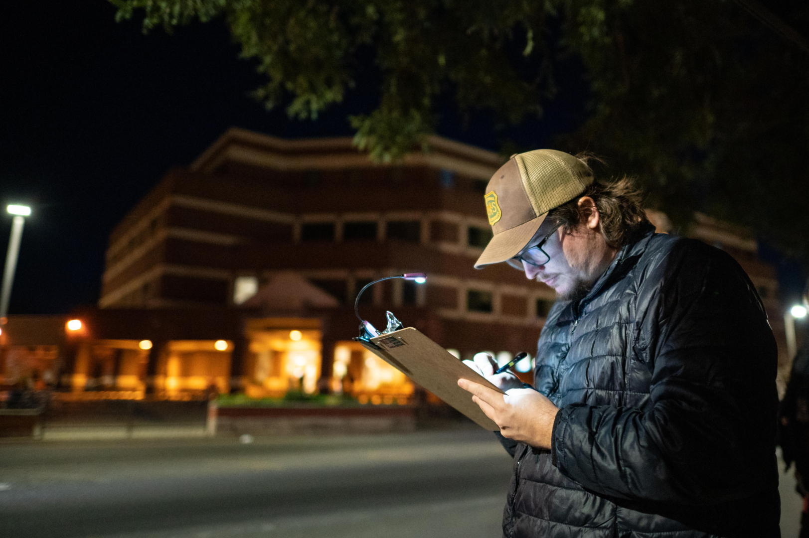 Jacob Winslow marks safety concerns using a clipboard with a clip-on light during the Moonlight Safety Walk.