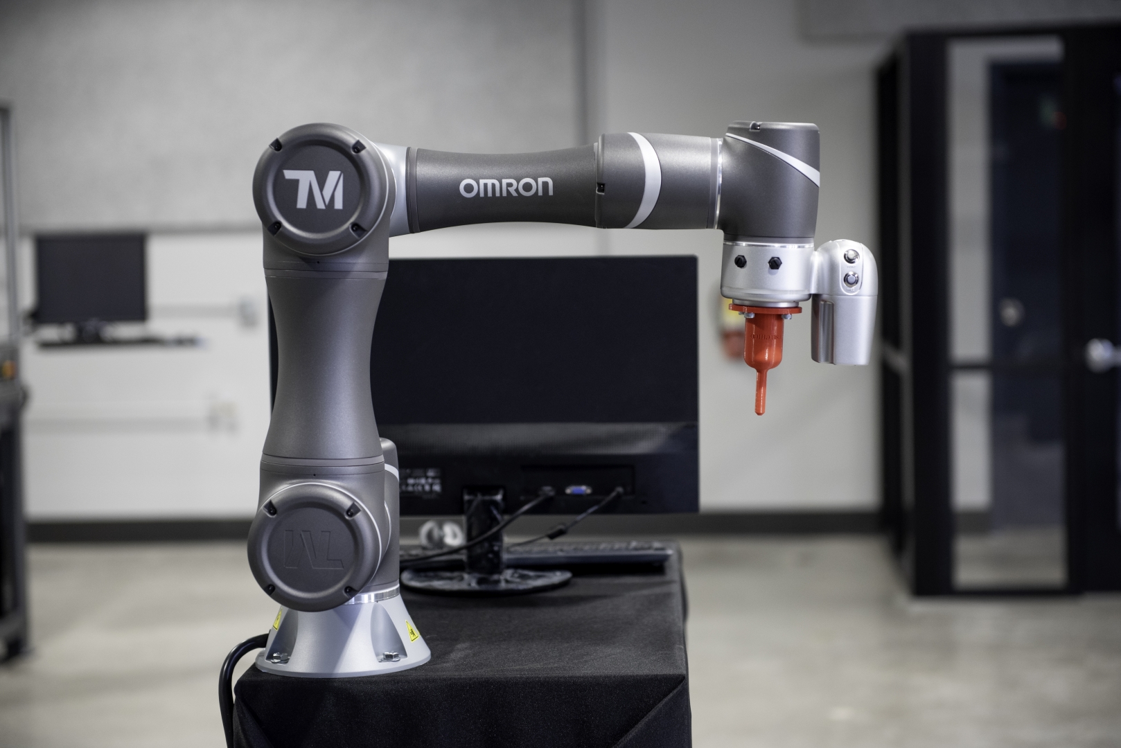 A robotic arm sits on a table next to a computer.