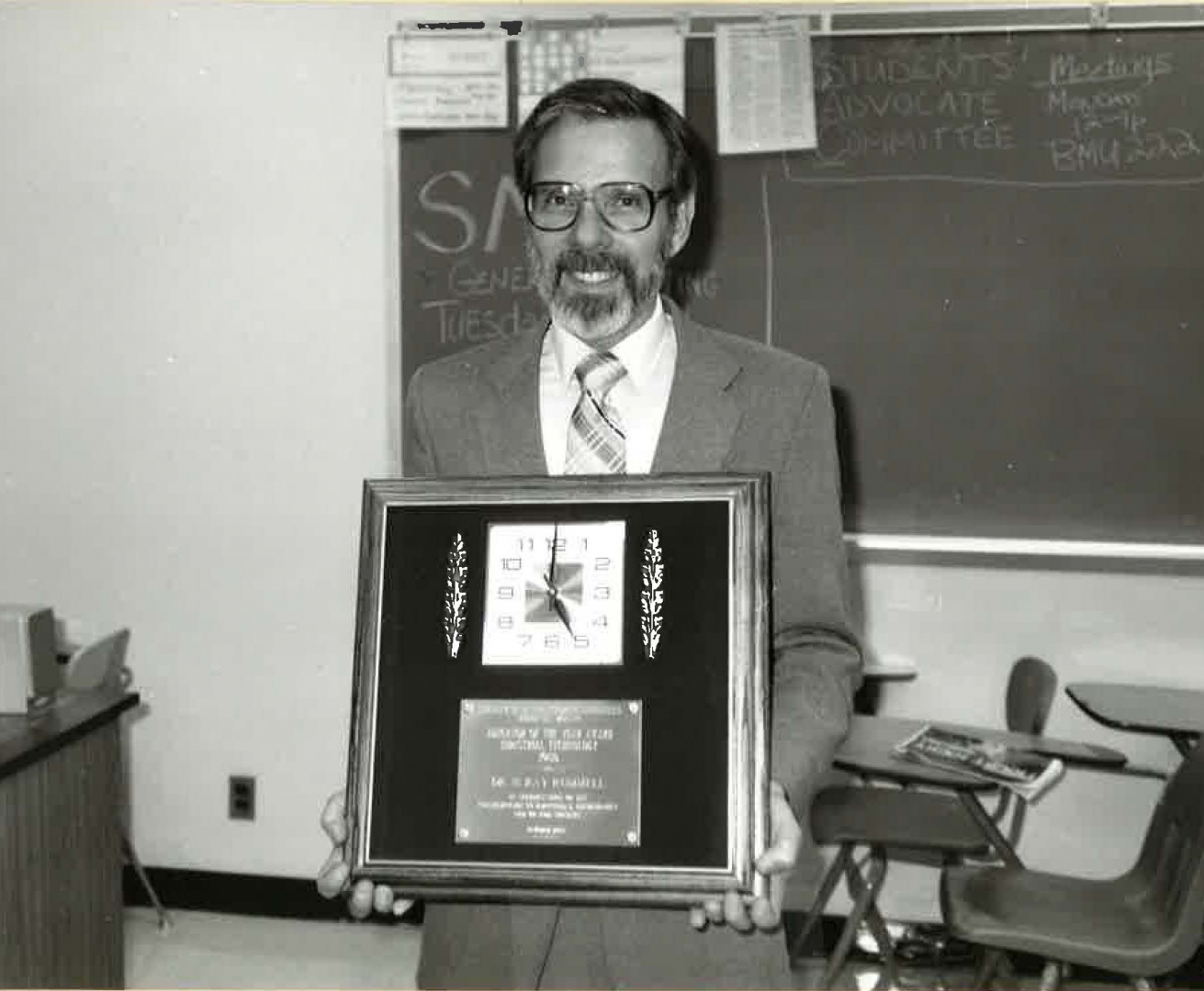 Ray Rummell stands with a framed award. 