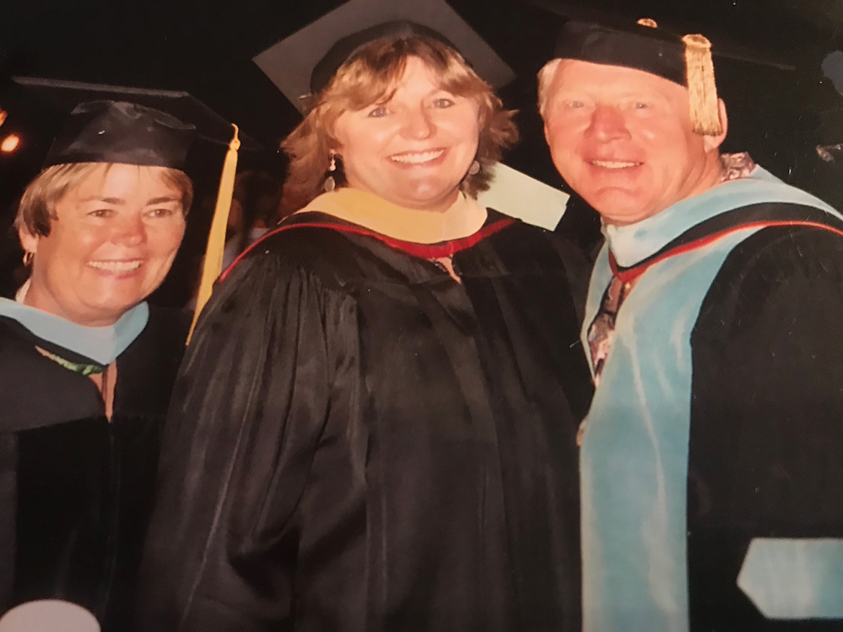 Robert Dionne, right, and Cindy Paxton, left, pose with his daughter Trynn at her master's Commencement in 2003. All are wearing graduation regalia.