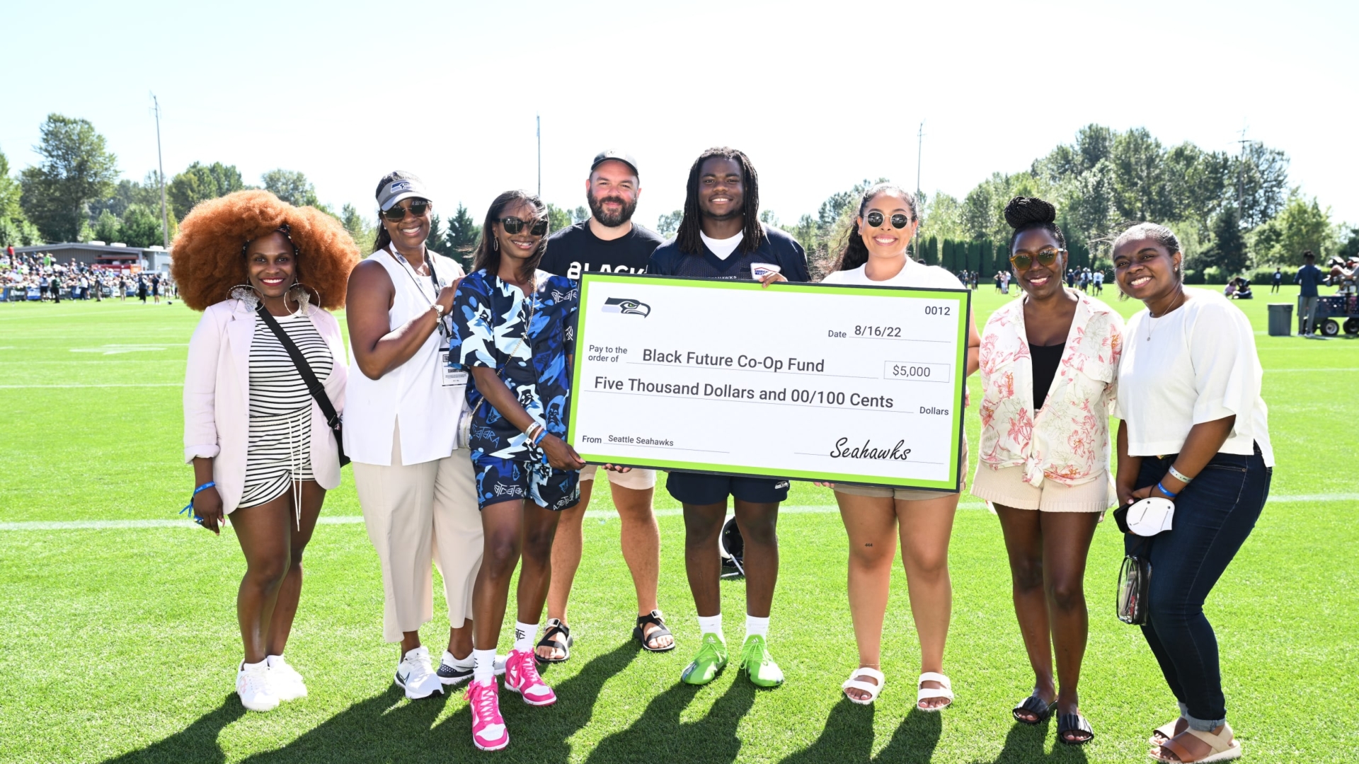 Eight people smile as they hold a giant check for the Black Future Co-Op Fund.