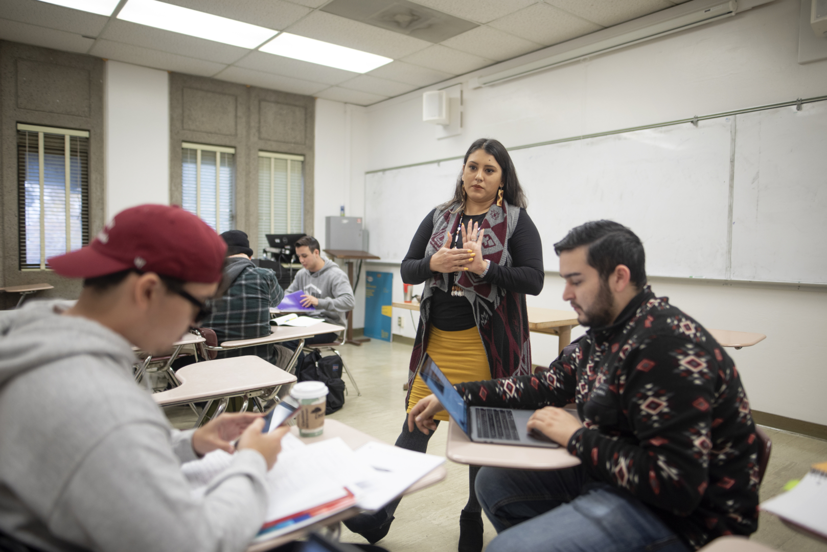 Professor of American Indian studies Vanessa Esquivido stands next to students discussing work in her class.