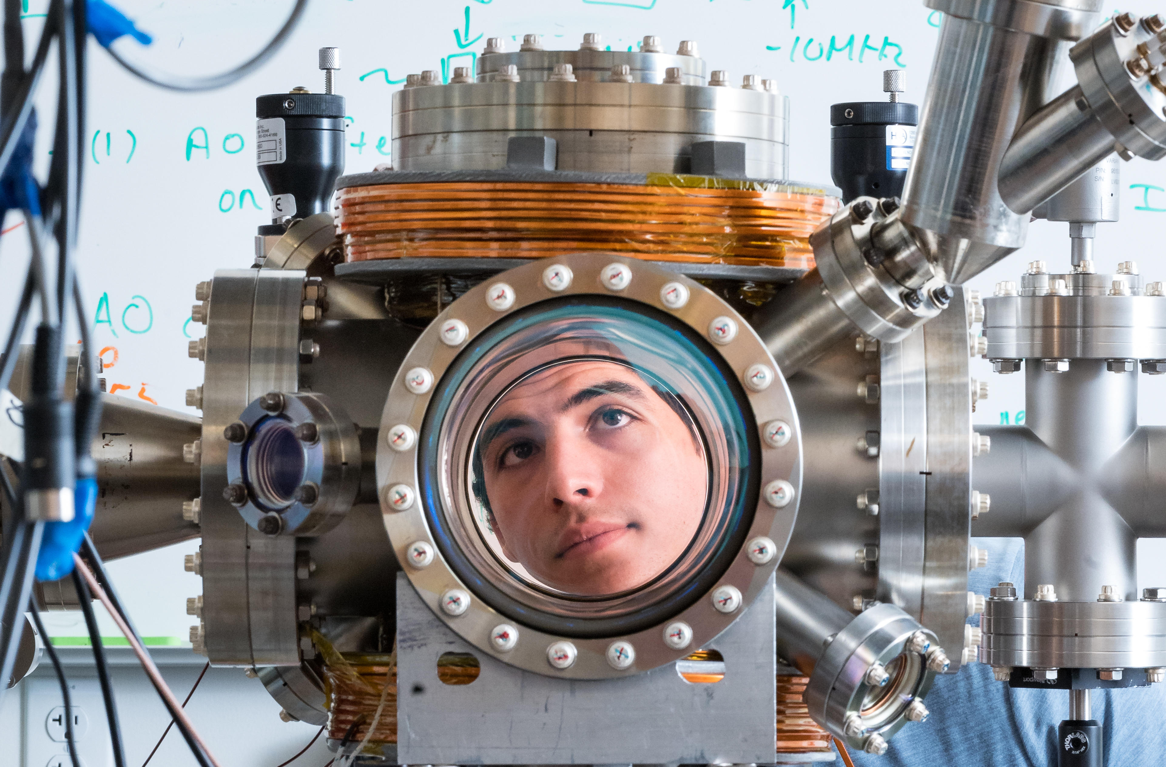 Nicholas Esparza looks through the high vacuum chamber in the ultracold lab.