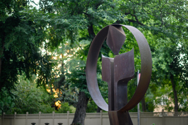 A sculpture sits in the foregrounds with lush trees in the background