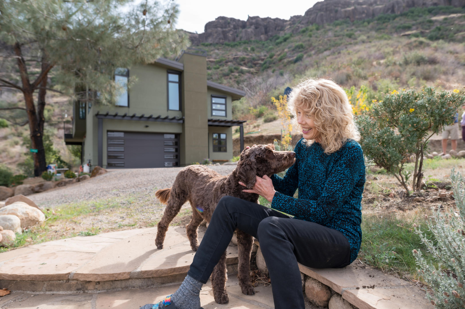 Cindy Wolff smiles as she rubs her hands along her dog's ears and throat as they sit on a walkway outside their new home.