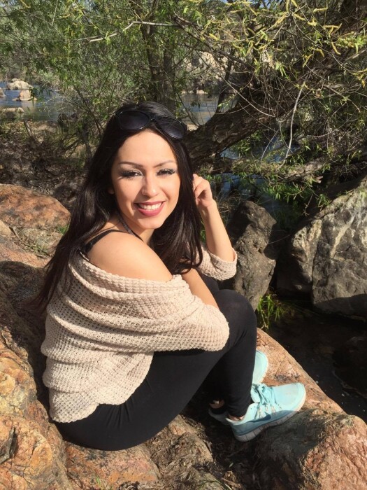 Gabriela Sanchez sits on a rock and smiles for the camera.