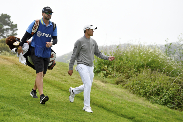 JJ Jakovac walks on a golf course with Collin Morikawa.